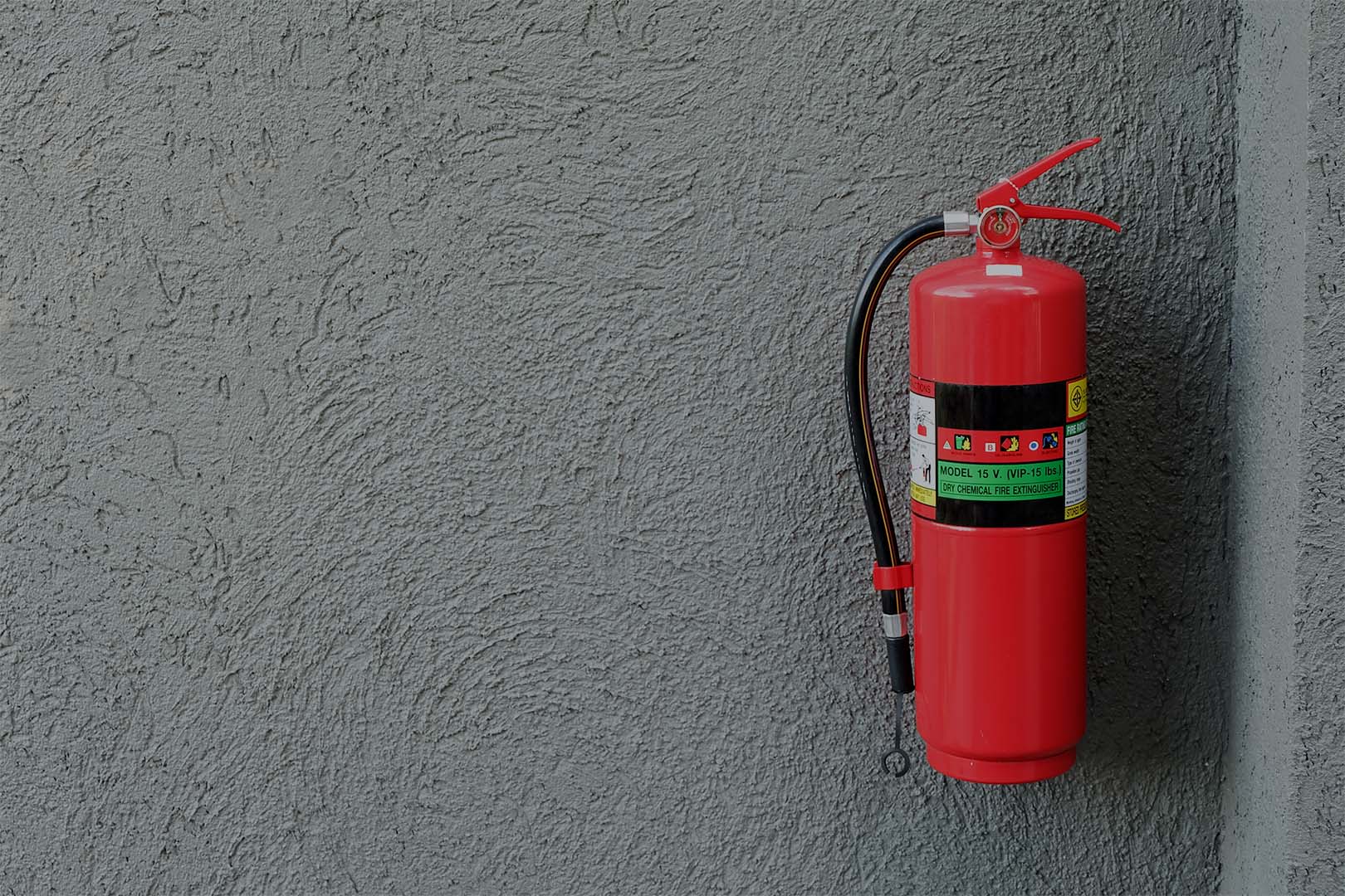 Fire extinguisher on the gray cement wall.